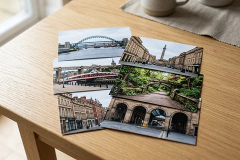 photo prints newcastle – a loose fan of 10×15 cm photo prints of Newcastle street scenes on a pale wooden table