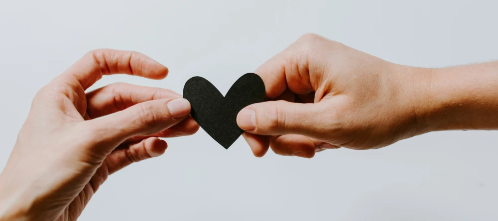 mains d'un couple tenant un coeur en papier
