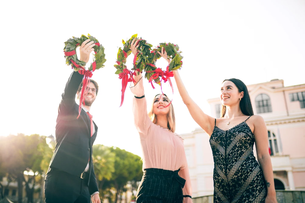 Ragazza laureata con corona d'alloro sorride felice, con il titolo '150+ Frasi Laurea e Auguri di Laurea' sullo sfondo