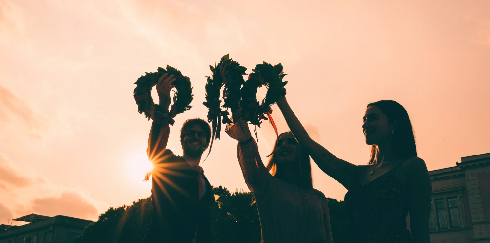 Gruppo di amici festeggia una laureata con coriandoli e corona d'alloro, simboleggiando le congratulazioni per la laurea
