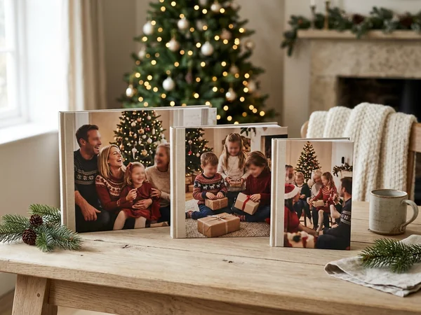 Christmas photo books in three sizes on a table beside a Christmas tree