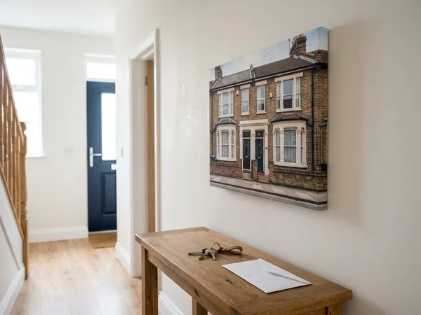 New home canvas print of a house frontage hanging in a hallway